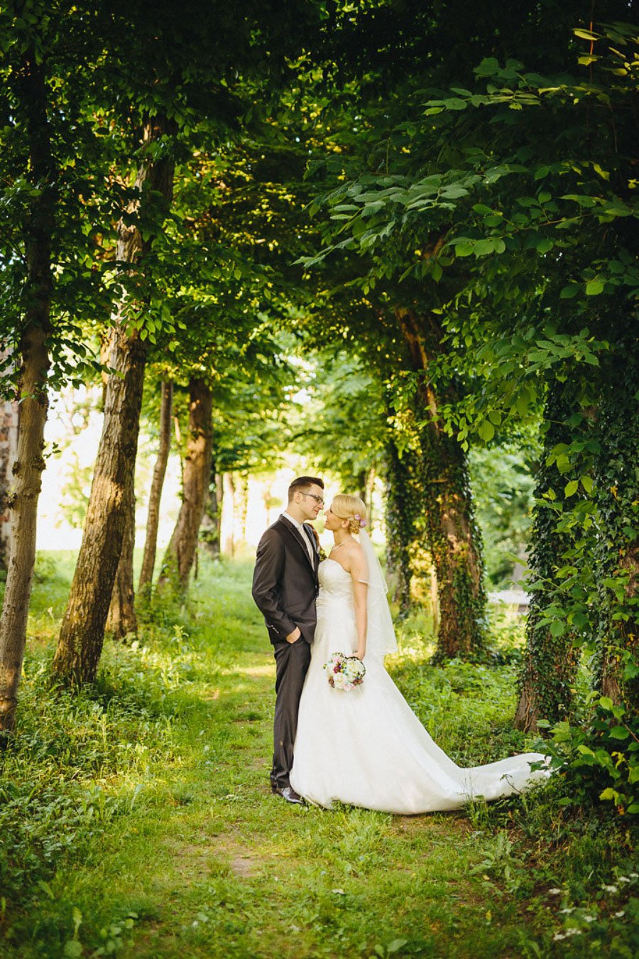 Braut und Bräutigam stehen unter Bäumen