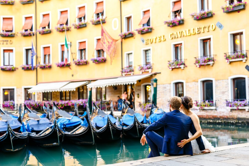 Braut und Bräutigam schauen in Venedig auf Gondeln