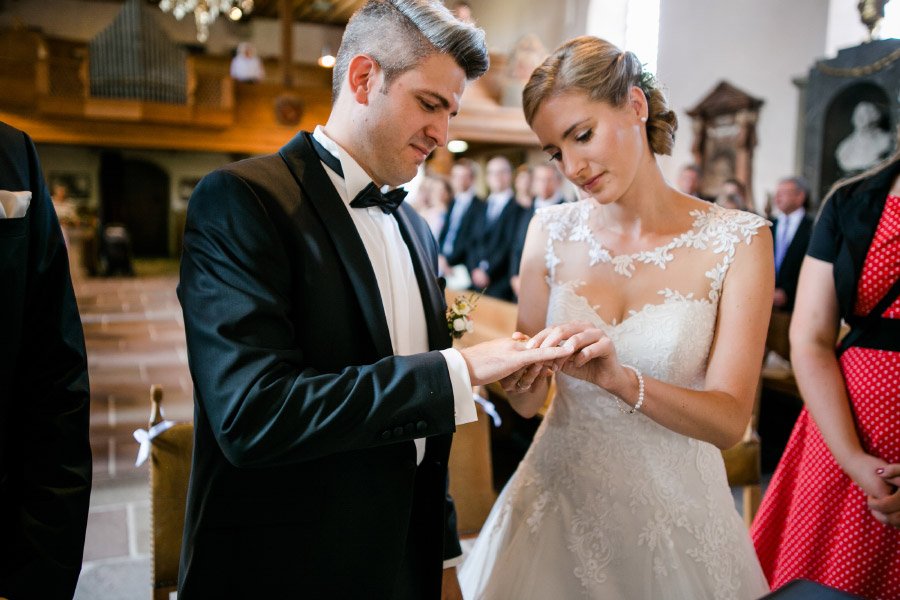 Braut steckt Bräutigam Ehering während der Trauung an