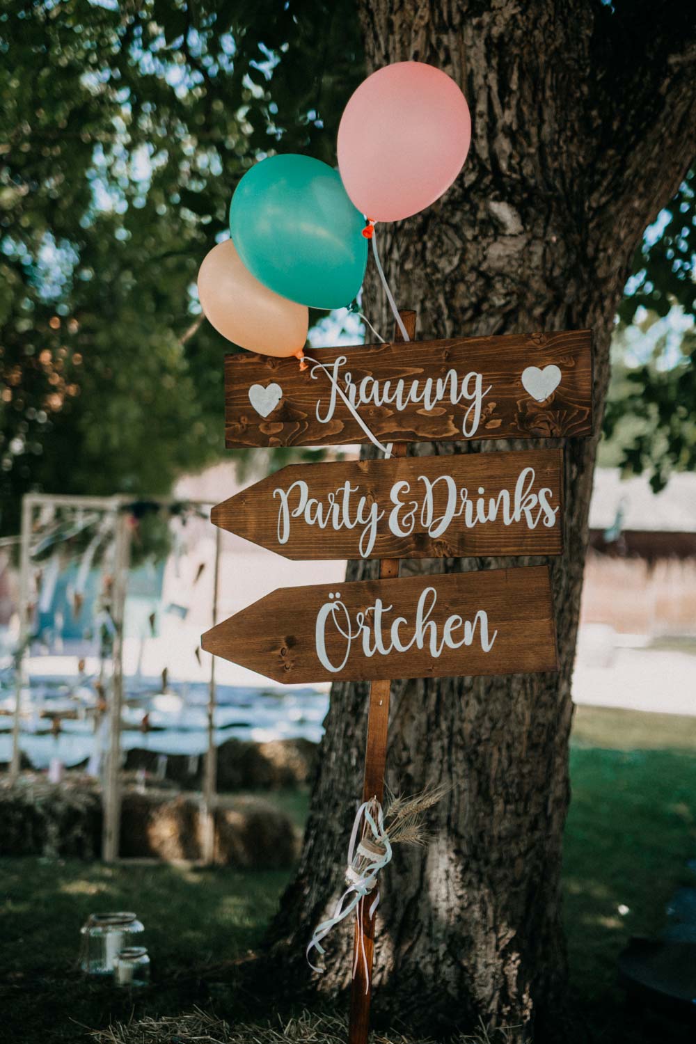 Holzschild als Wegweiser bei der Boho-Hochzeit auf dem Bauernhof