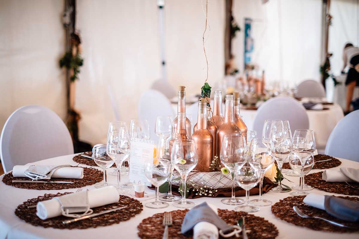 Tischdekoration mit besprühten Flaschen bei der Hochzeit