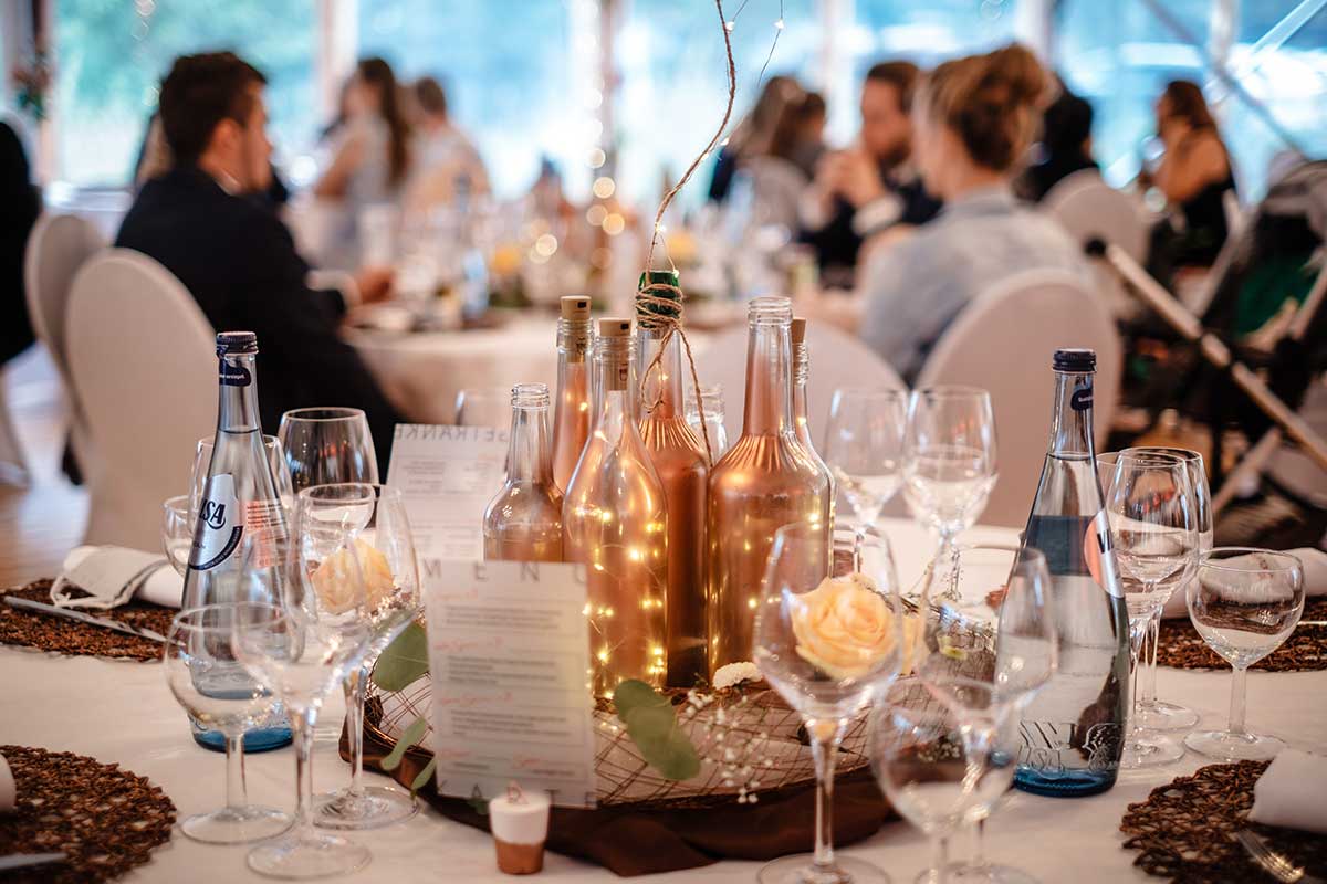 Tischdekoration mit besprühten Flaschen bei der Hochzeit