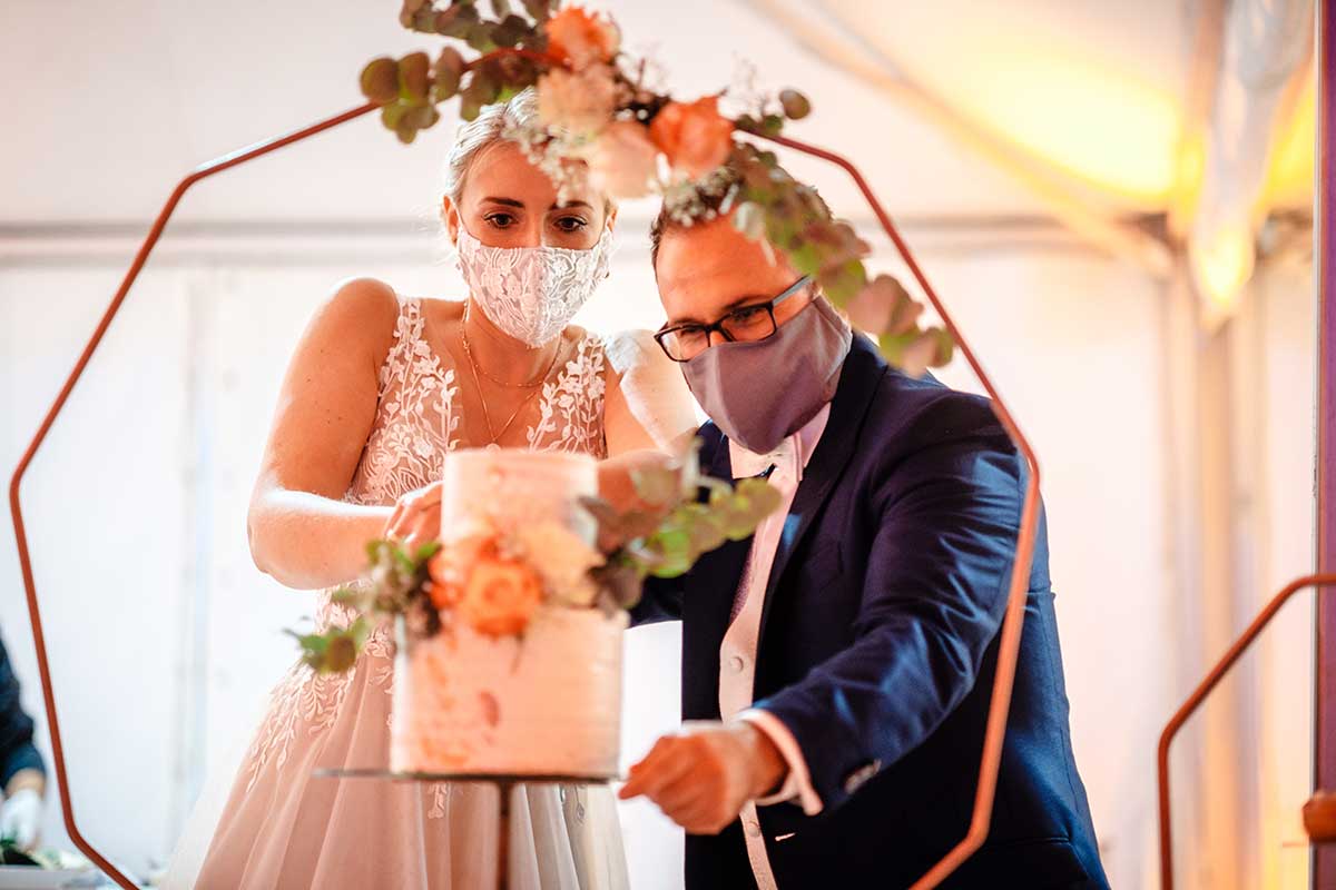 Braut und Bräutigam schneiden Hochzeitstorte an