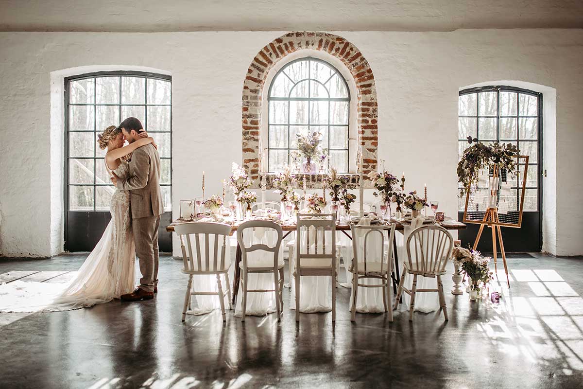 Brautpaar steht neben gedecktem Tisch