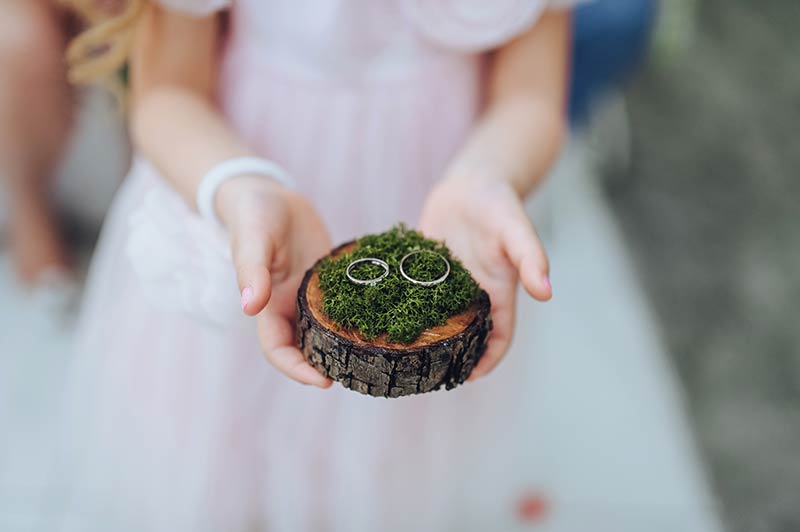 Kind bringt Ringe auf einer mit Moos bedeckten Holzscheibe